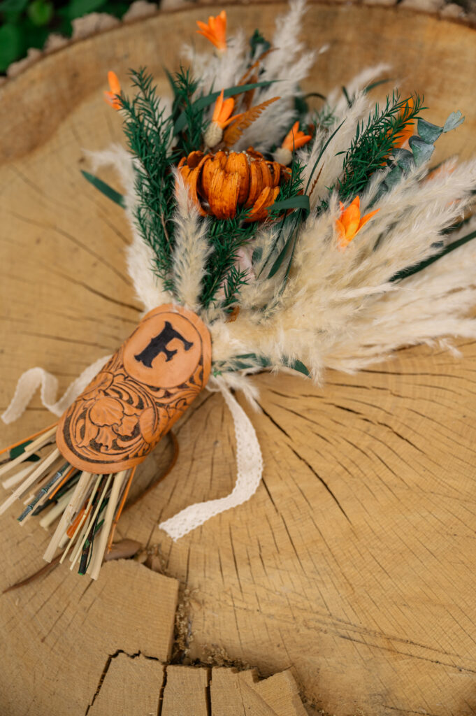 dried bridal bouquet and western tooled leather wrap wedding flat lay